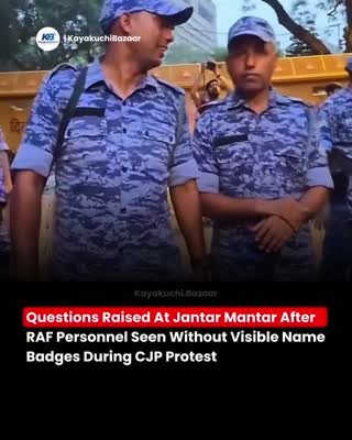 Still from the clip: paramilitary personnel in blue camouflage uniforms, with a news caption about missing name badges.